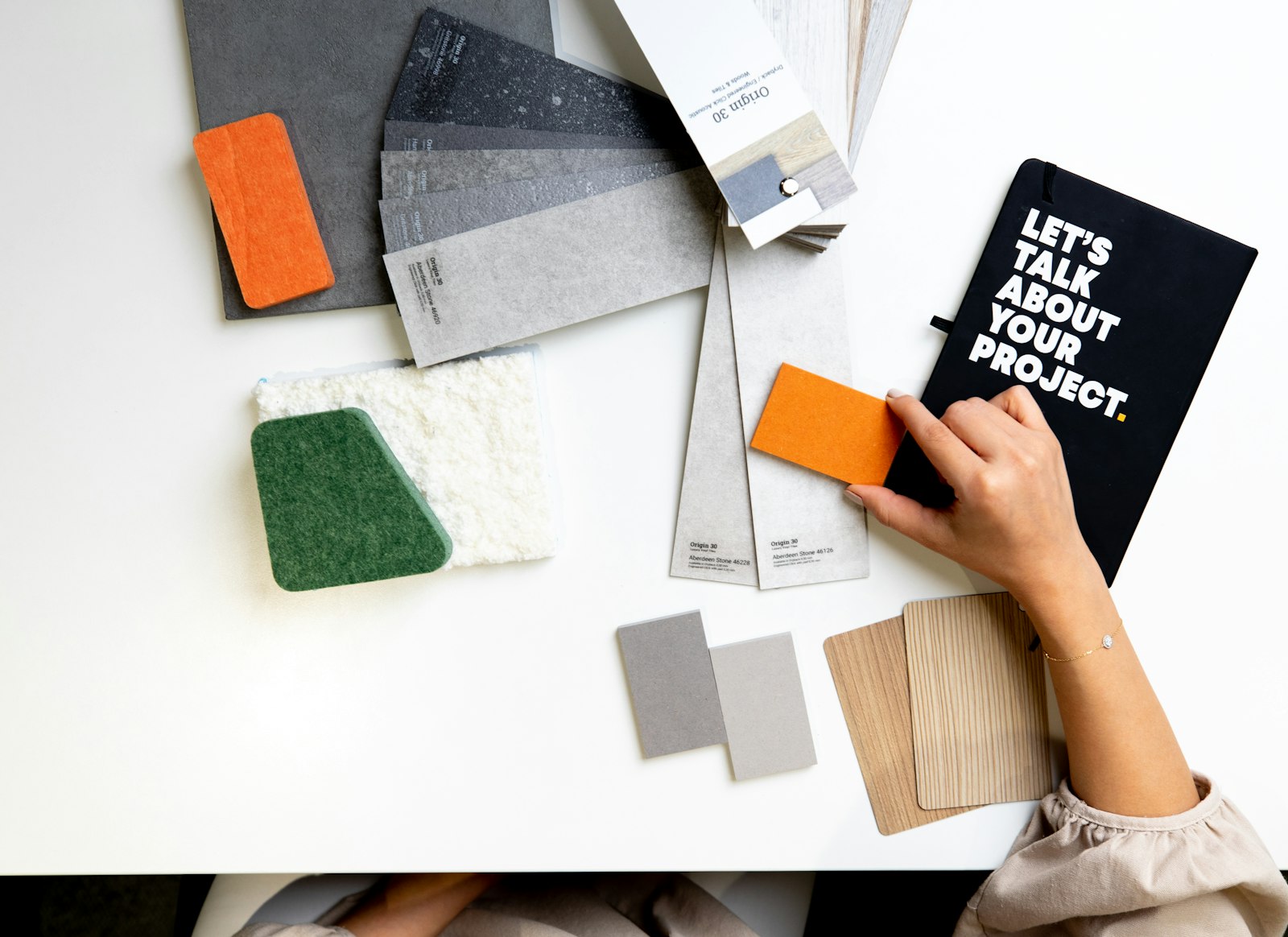 Designer holding a material sample over a desk of interior design swatches